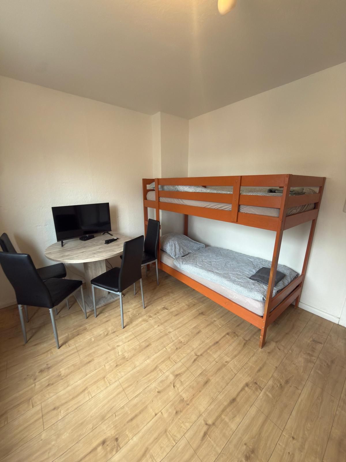 Ein Zimmer mit einem Etagenbett, einem Schreibtisch mit Computer und zwei Stühlen.