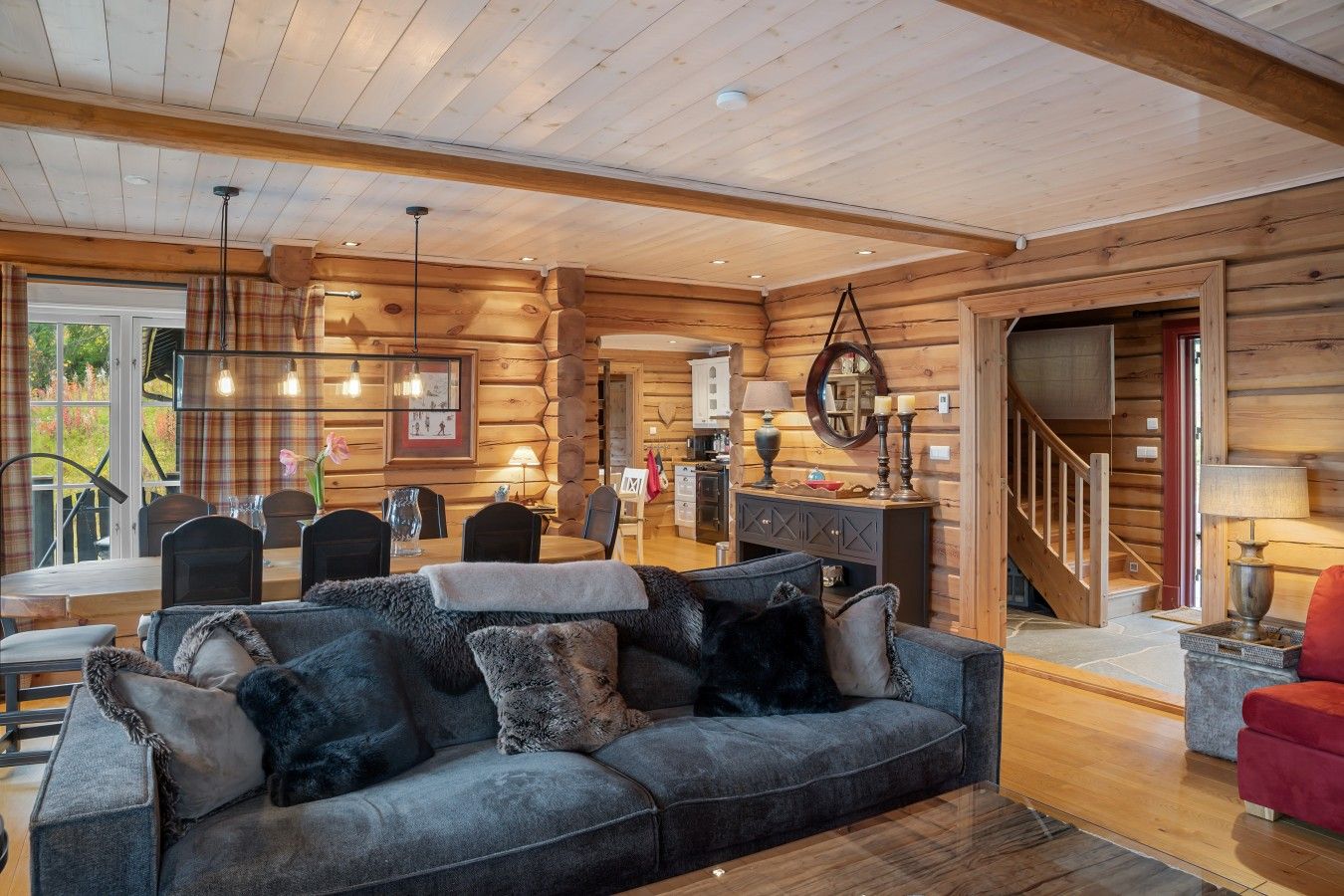 Ein Blockhaus-Interieur mit einer Couch, einem Esstisch und einer Küchenzeile.