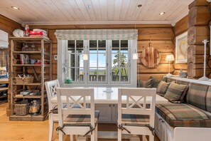 L’intérieur d’un chalet accueillant, avec une table à manger, des chaises, un canapé et une bibliothèque.