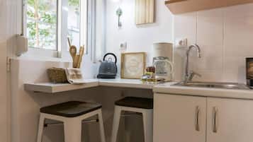 Una cocina con ventana, una cafetera y dos taburetes.