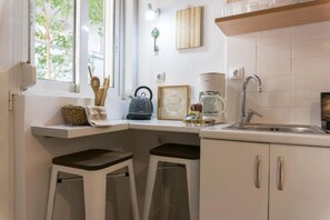 Una cocina con ventana, una cafetera y dos taburetes.