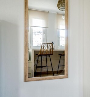 Una habitación con un espejo grande que refleja una silla y un ventanal.