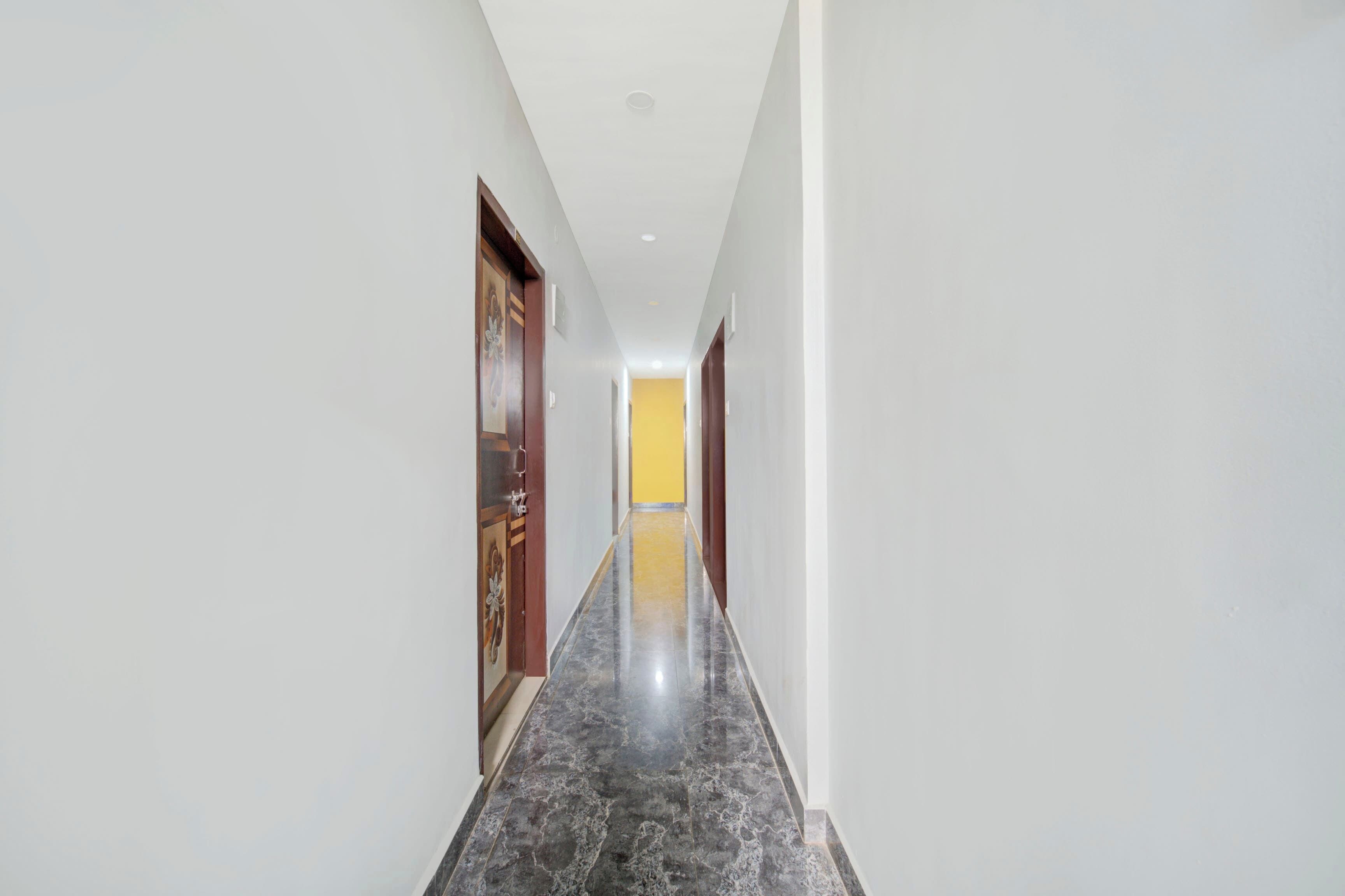 A corridor with a marble floor, white walls, and wooden doors.