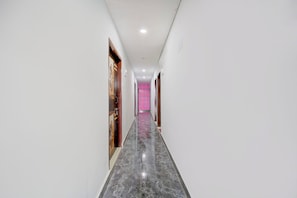 Un pasillo con piso de mármol que conduce a una habitación con pared de estampado rosado.