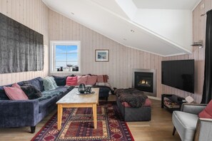 Ein gemütliches Wohnzimmer mit Kamin, großem Fernseher und einer komfortablen Sitzecke.