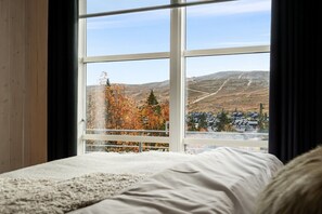 A bedroom with a large window offering a view of a mountainous landscape and a village below. - FA1084 Mountain retreat in Trysil, Sauna, 8 people (Trysil)