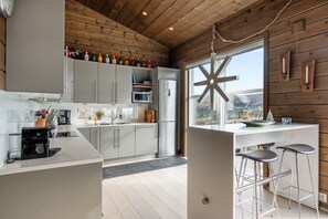 A modern kitchen with grey cabinets, a stainless steel refrigerator, and a bar area with stools. - FA1084 Mountain retreat in Trysil, Sauna, 8 people (Trysil)