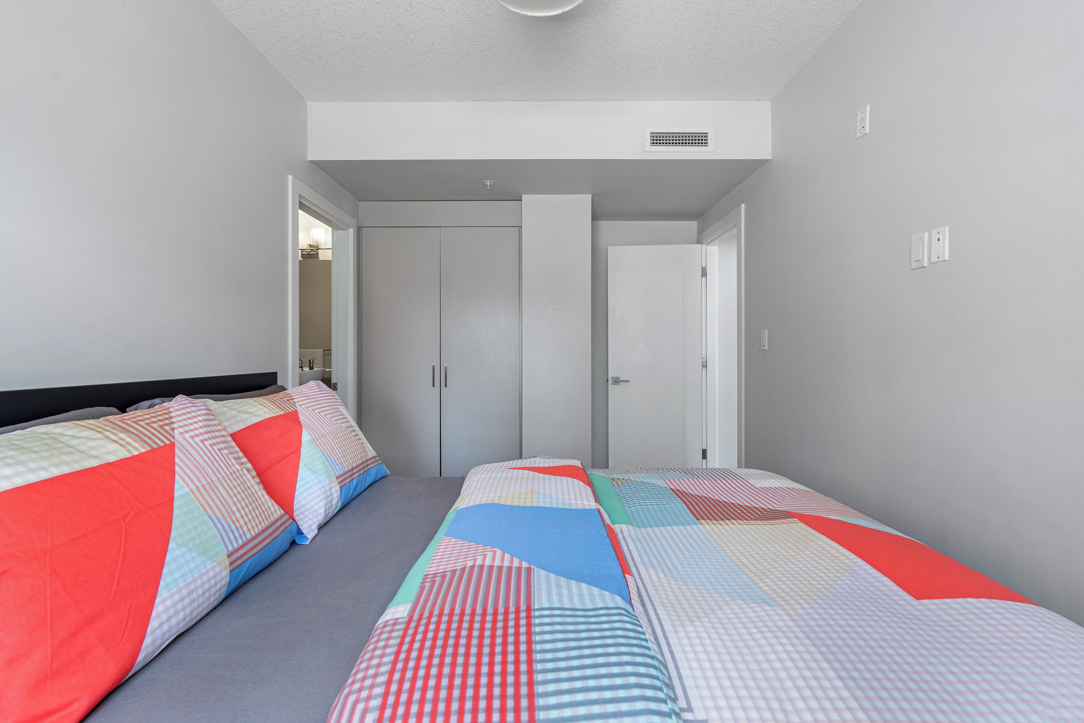 Un dormitorio con dos camas, un armario y una puerta que da a otra habitación.