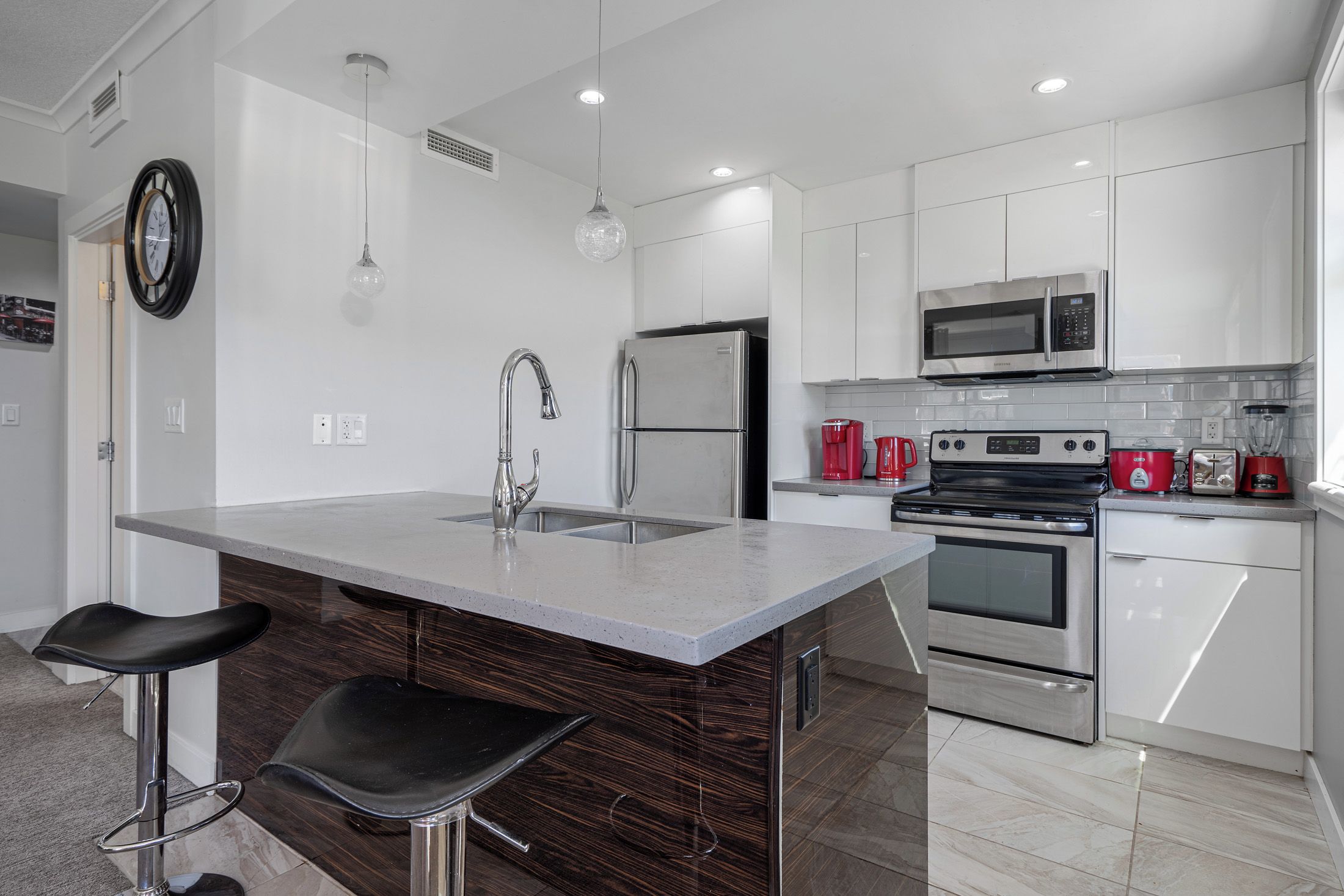 Una cocina moderna con una isla central, electrodomésticos de acero inoxidable y taburetes de bar.