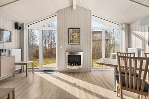 A modern interior with a fireplace, wooden flooring, and large glass doors leading to an outdoor area. - Baltic Aloha Hus: A Holiday Home 250 m from Grömitz Beach (Grömitz)