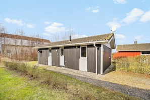 A single-story building with a tiled roof, a satellite dish, and a gravel driveway. - Baltic Aloha Hus: A Holiday Home 250 m from Grömitz Beach (Grömitz)
