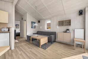 A modern, well-lit living area with a sofa, coffee table, and kitchen appliances. - Baltic Aloha Hus: A Holiday Home 250 m from Grömitz Beach (Grömitz)