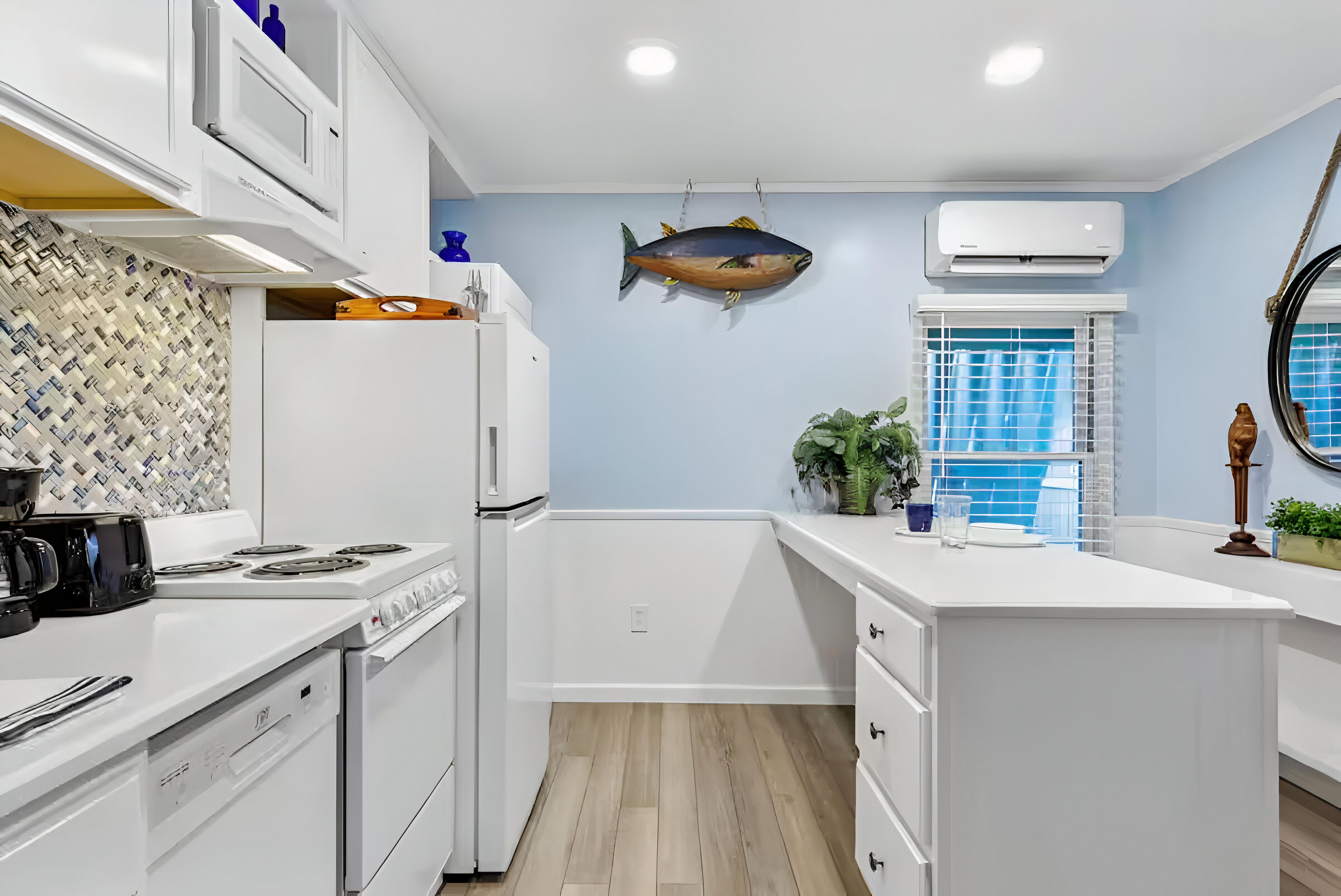 A modern kitchen with white cabinetry, a fish hanging on the wall, and a window with blue shutters.