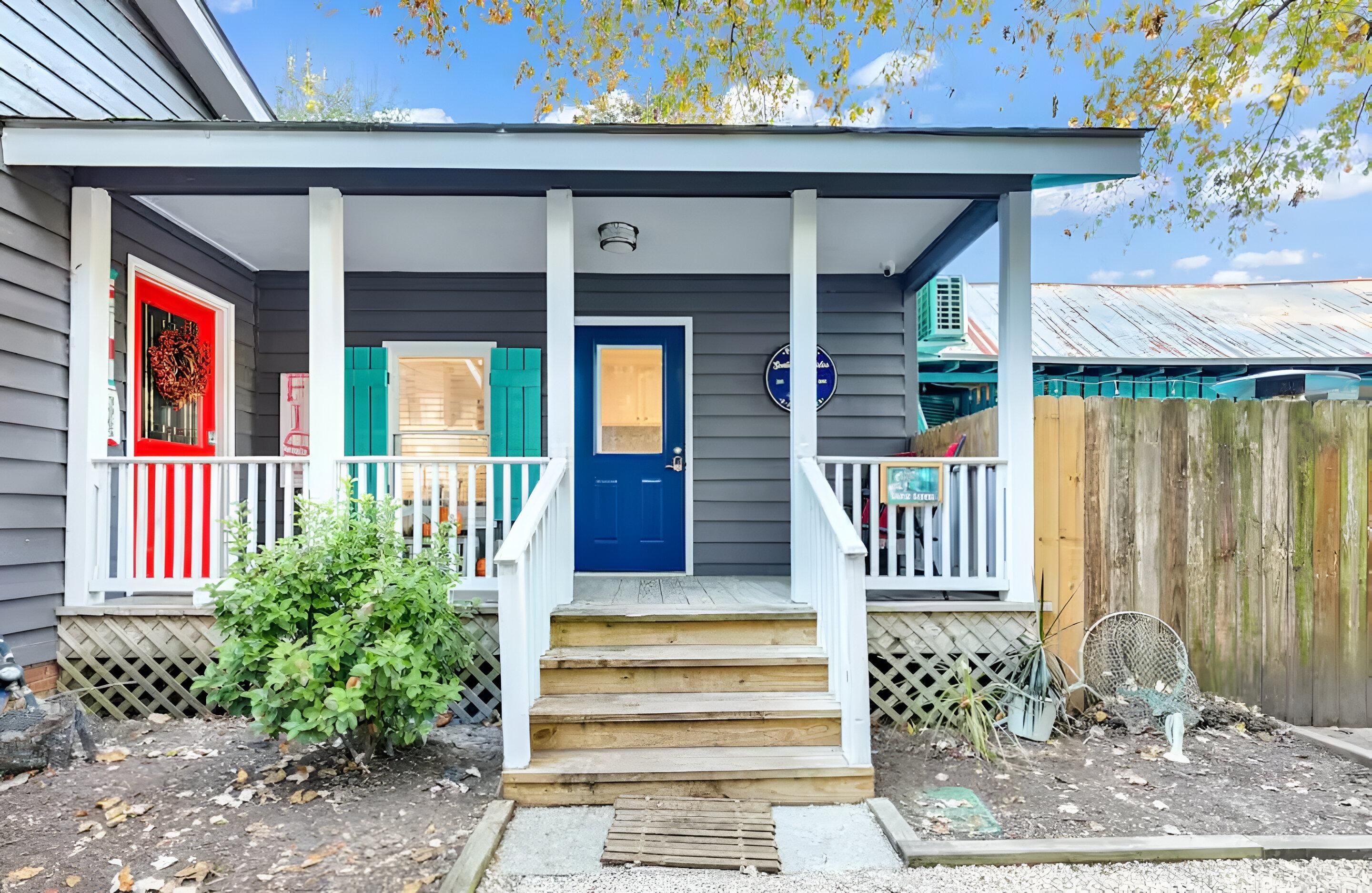 Une maison avec un porche, une porte bleue et une boîte aux lettres rouge.