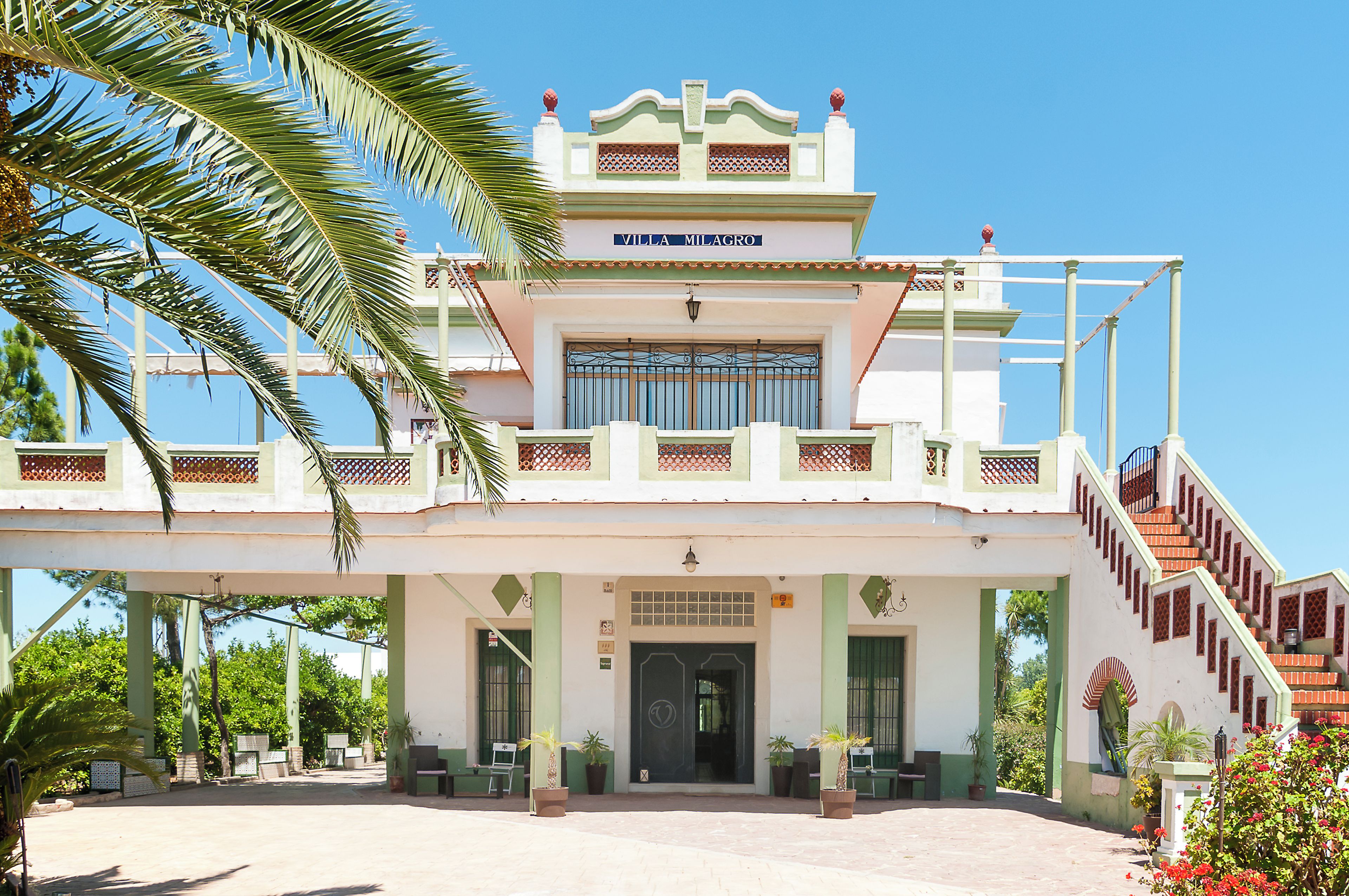 Um edifício de dois andares com uma placa que diz 'Villa Milagro' no topo.