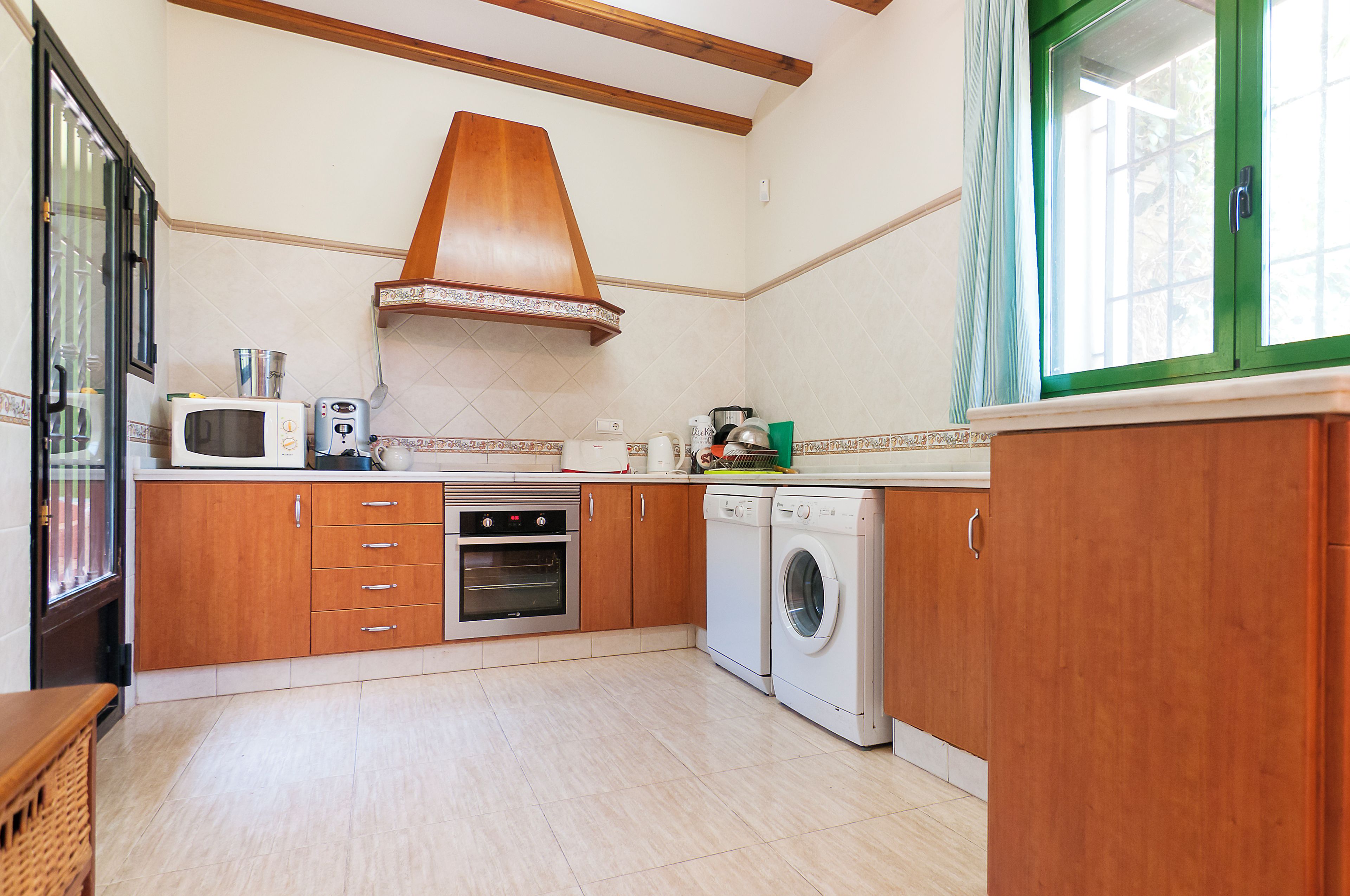 Cozinha com armários de madeira, micro-ondas, forno e máquina de lavar.