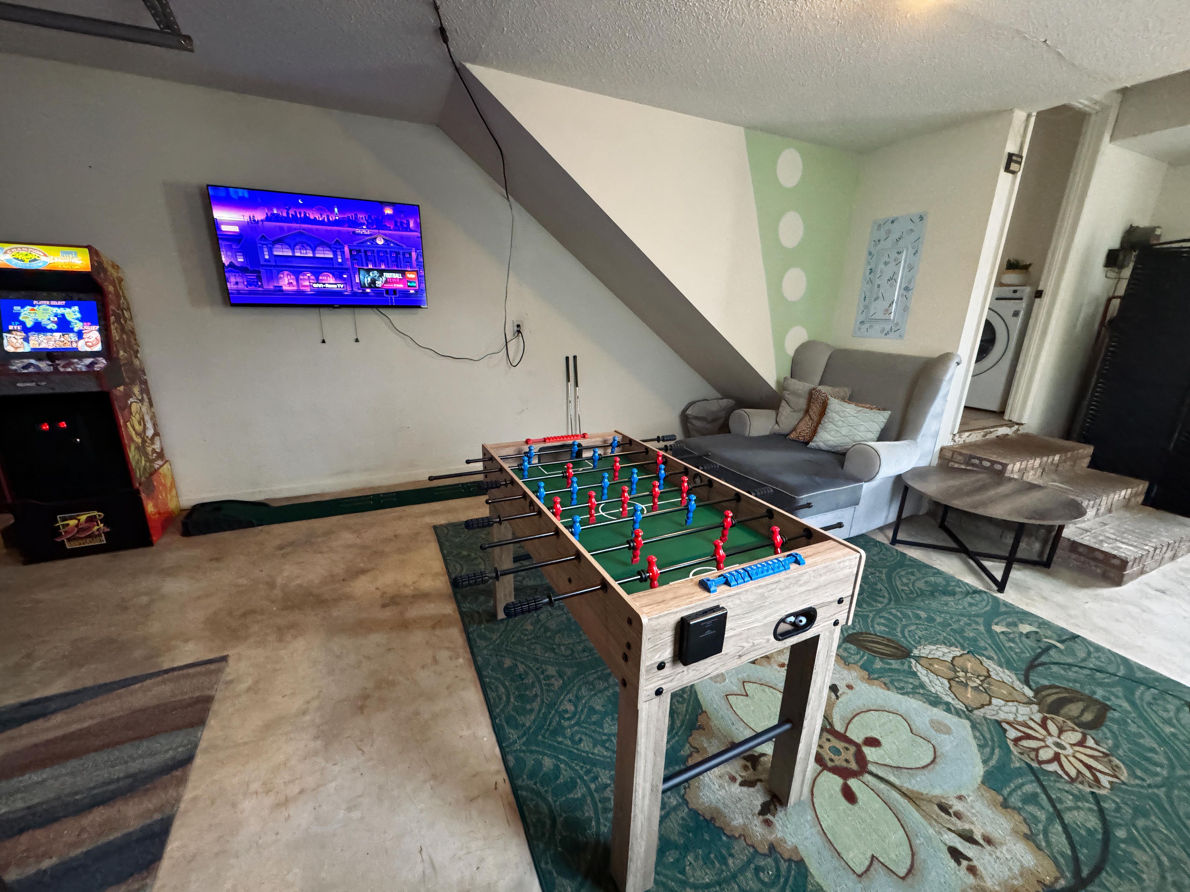 Ein Zimmer mit Kicker, Fernseher und einer Couch.