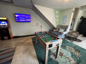 A room with a foosball table, a television, and a sofa. - Plush in the Pines!  - 4BR + Game Room (Ladson)