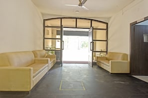 A reception area with a curved wall, two sofas, a ceiling fan, and a 'No Admission' sign.