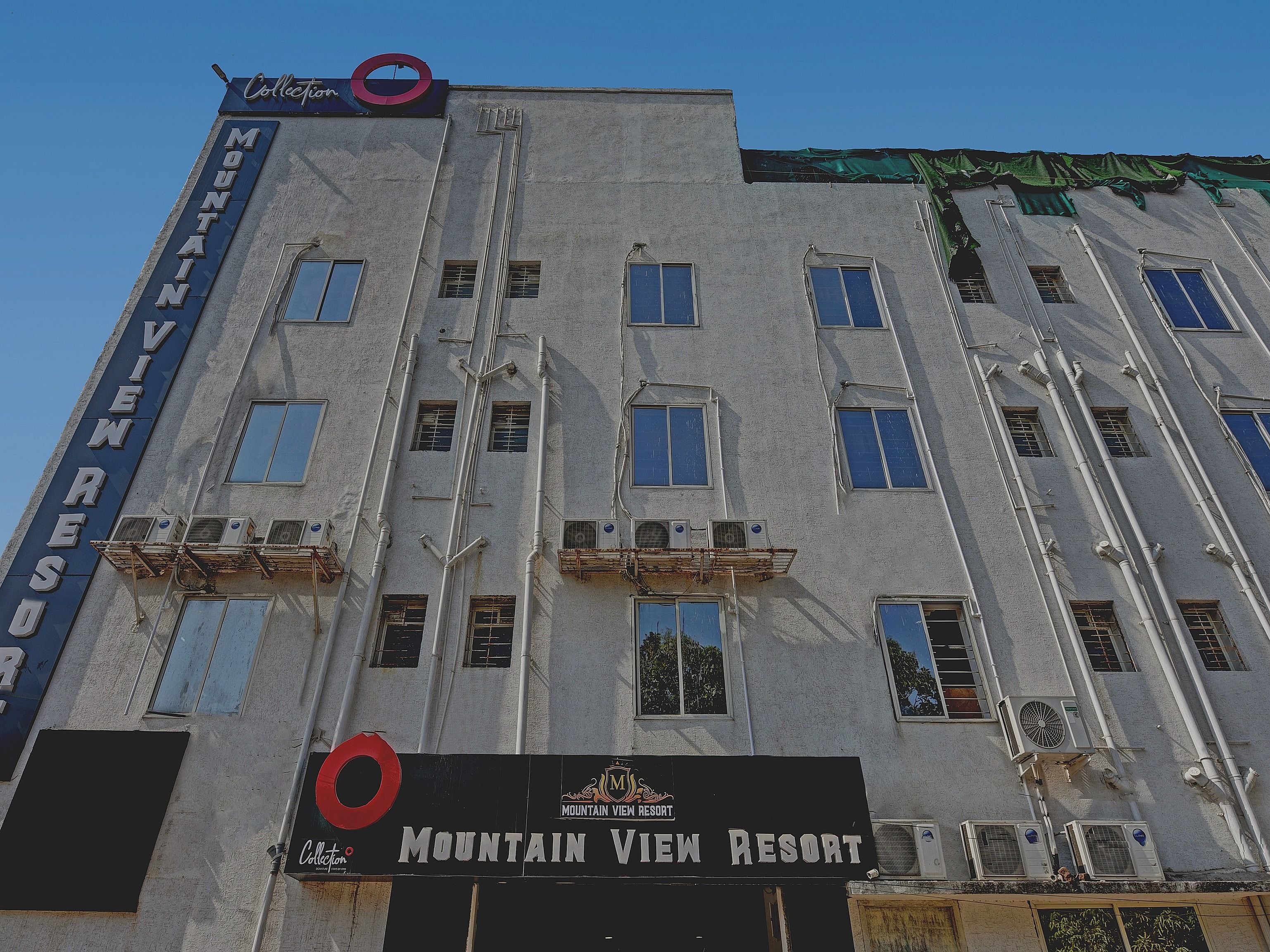 Un edificio con múltiples ventanales, un cartel que dice 'Mountain View Resort' y un logotipo con un círculo rojo.