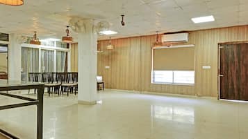 A spacious room with a tiled floor, a large window, and a door. There are ceiling fans and a hanging light fixture.