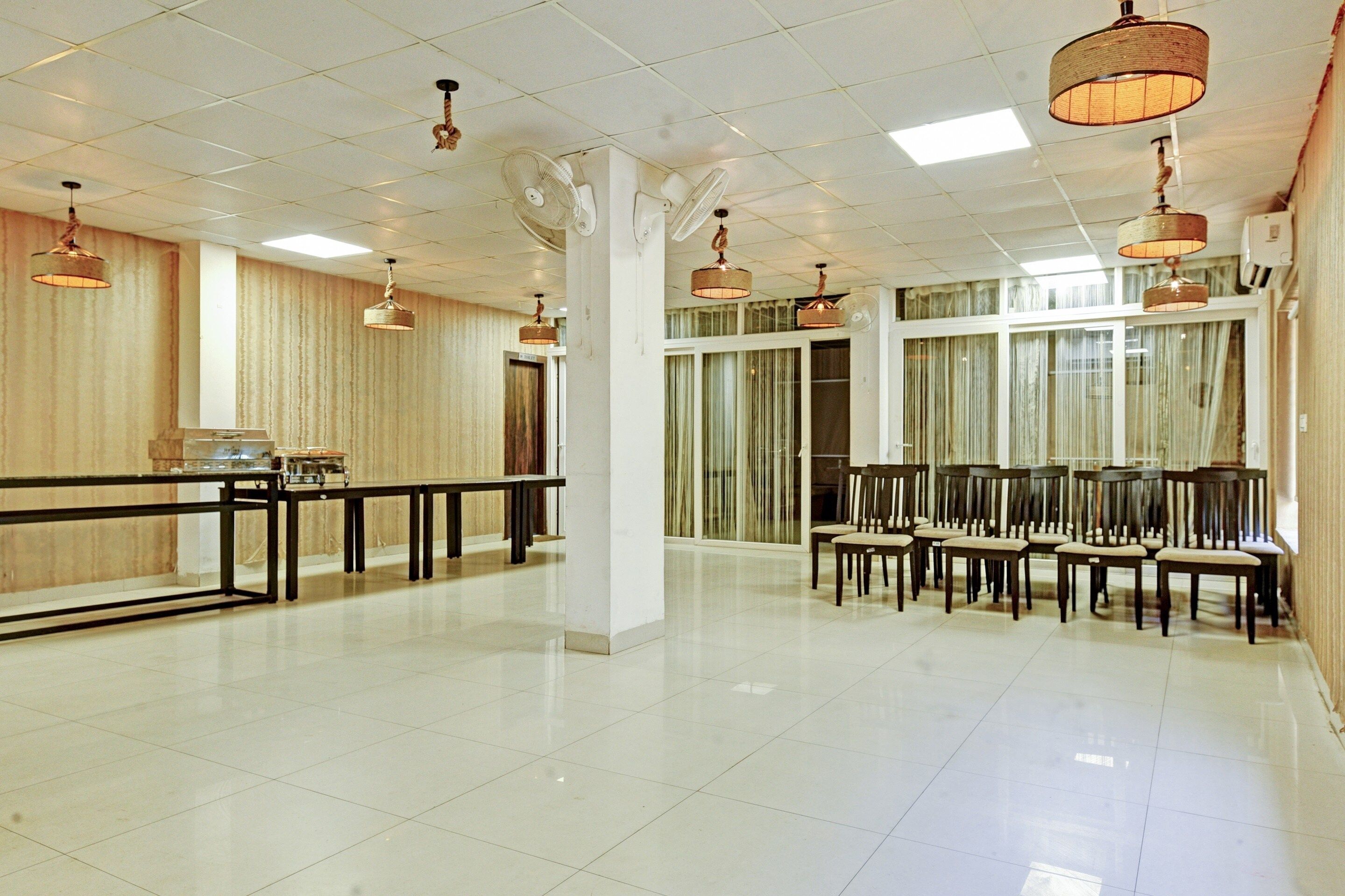 Un amplio vestíbulo de hotel con techo alto, luminarias modernas, una recepción y una zona de estar con sillas.