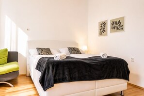 A hotel room with a bed, a chair, and artwork on the wall. - Your Vienna Escape 2BR near Belvedere and Rennweg (Vienna)