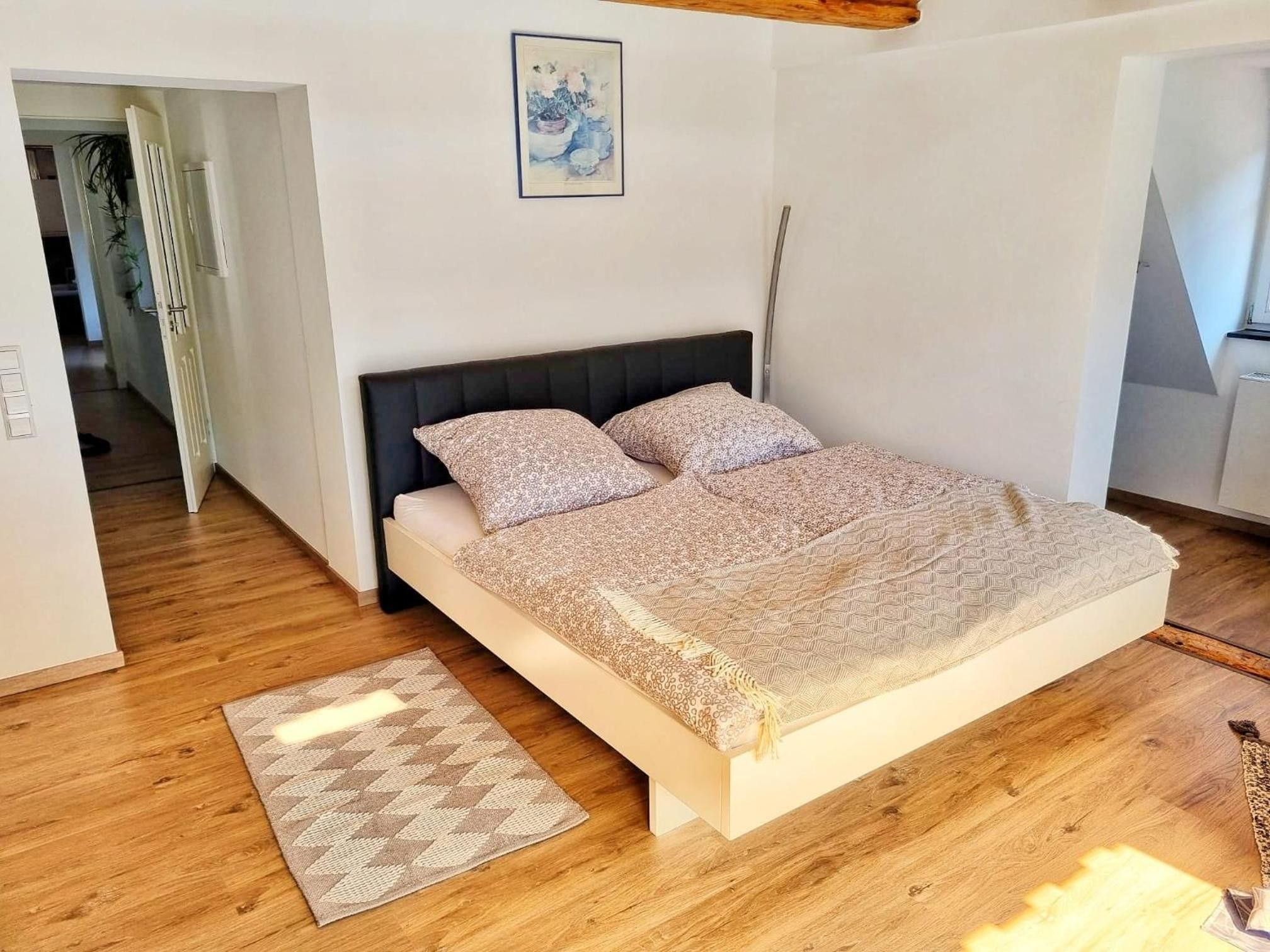 Ein Schlafzimmer mit einem Bett, einem Teppich und einem Bild an der Wand.