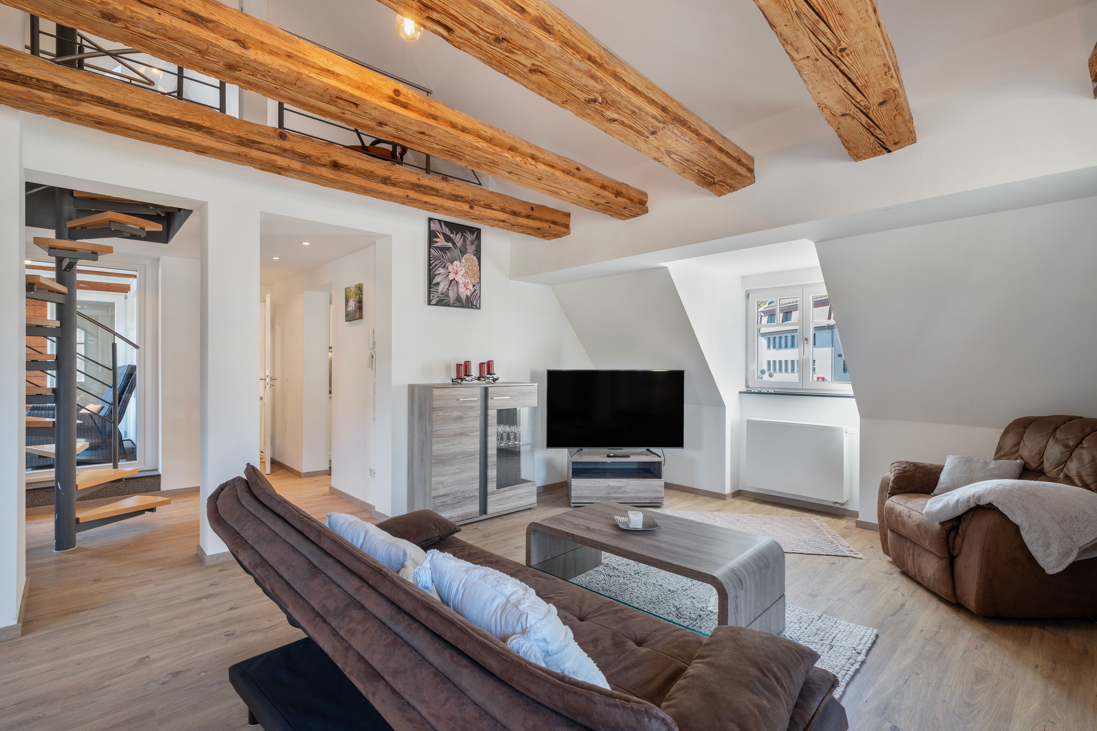 Een moderne woonkamer met een flatscreen televisie, een bank en een bruine leren fauteuil.