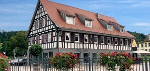 Ein traditionelles Fachwerkhäuschen mit einem steilen Satteldach, zahlreichen Fenstern und einem verschlossenen Eingang.