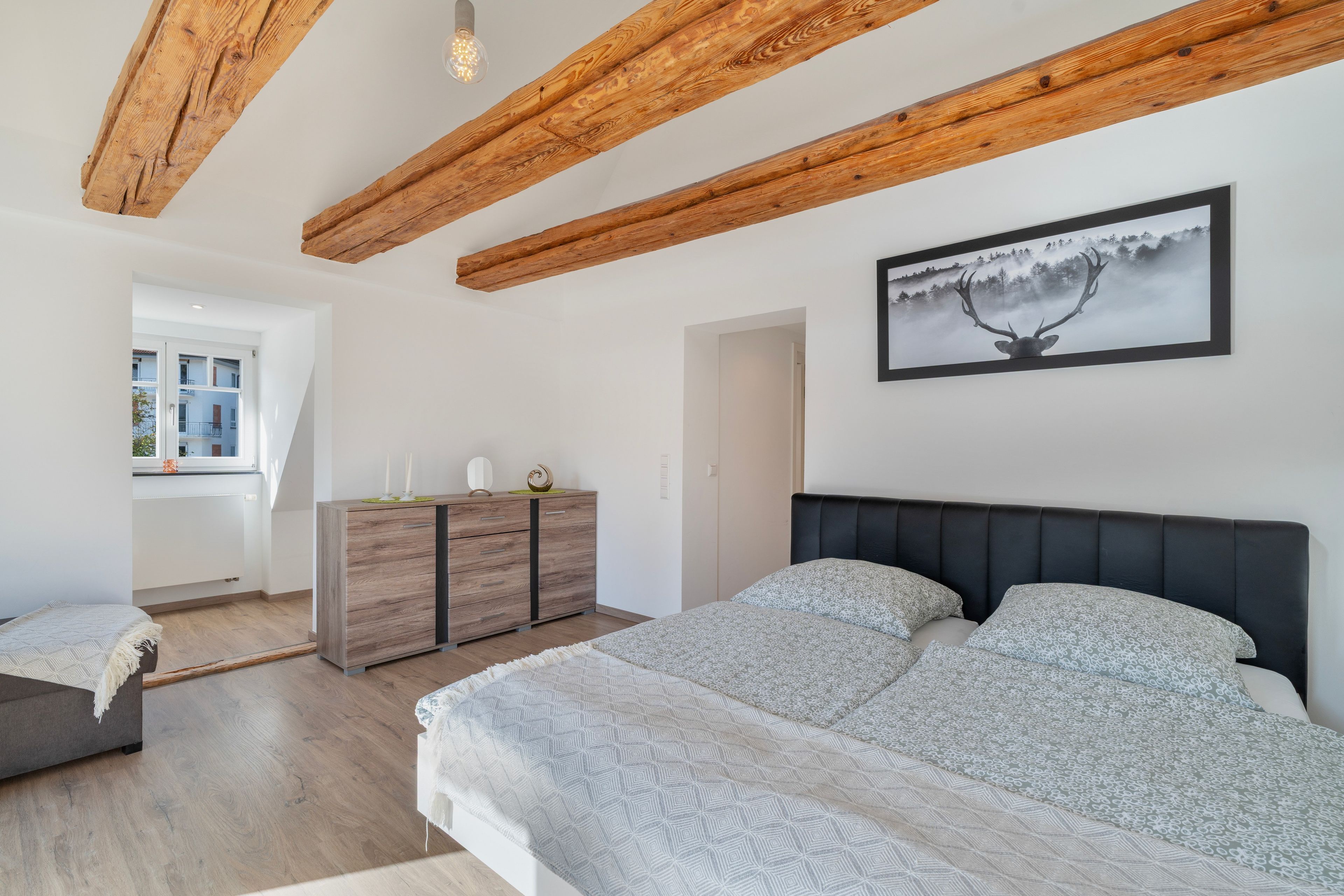 Une chambre à coucher avec un lit, une commode et un tableau accroché au mur.