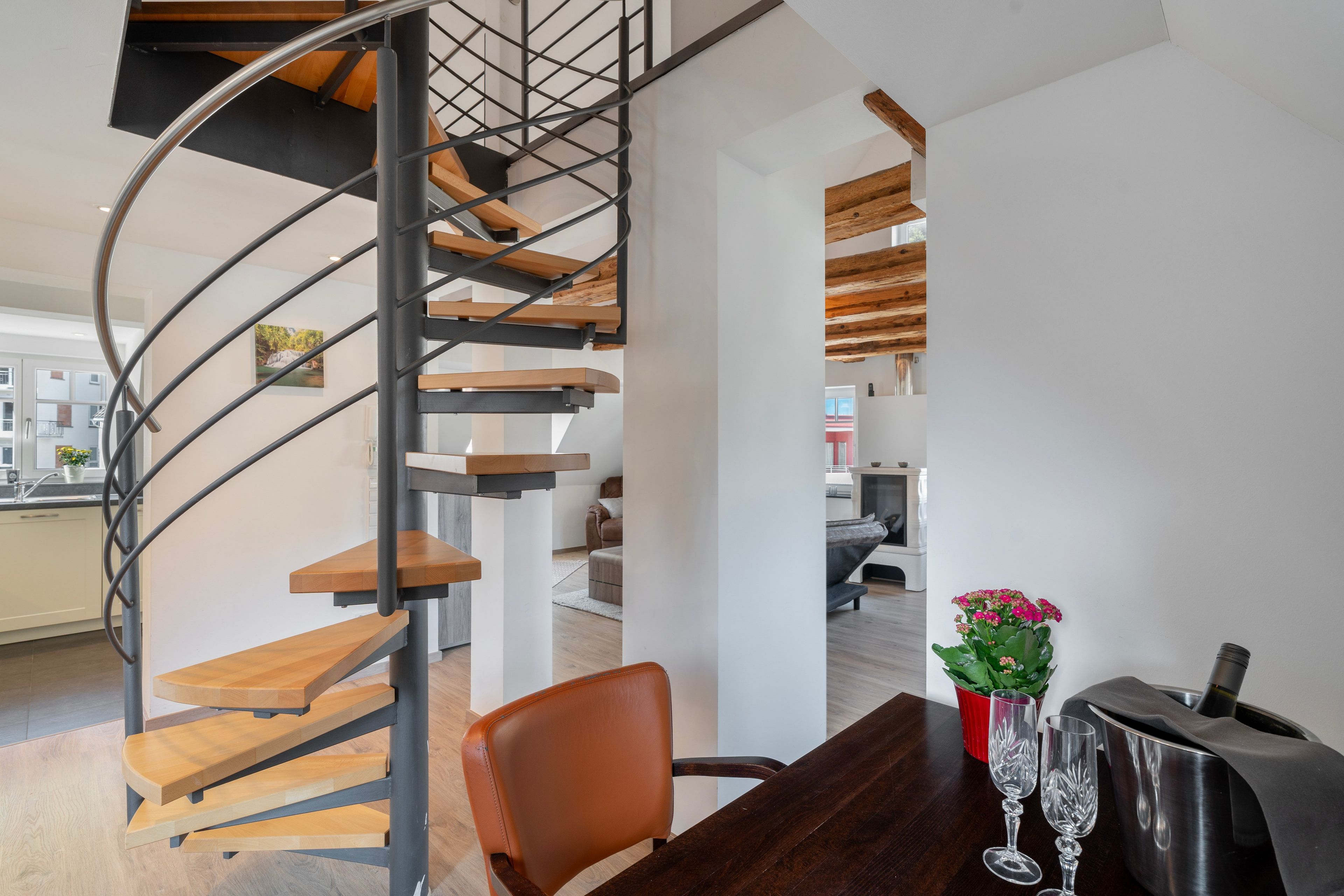 Een modern interieur met een spiltrap, een eethoek en zicht op een andere kamer.