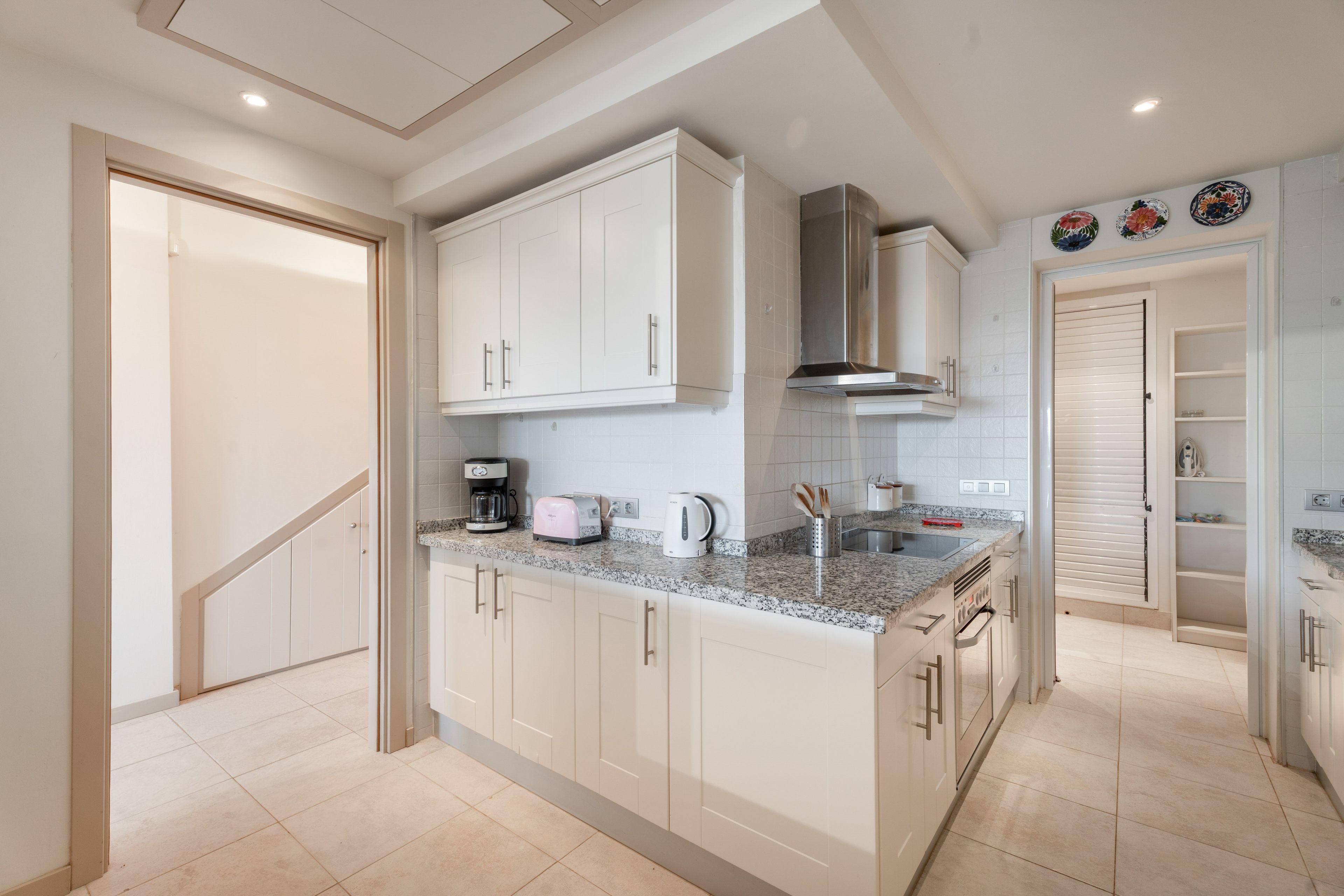 A modern kitchen with white cabinets, a granite countertop, and stainless steel appliances.