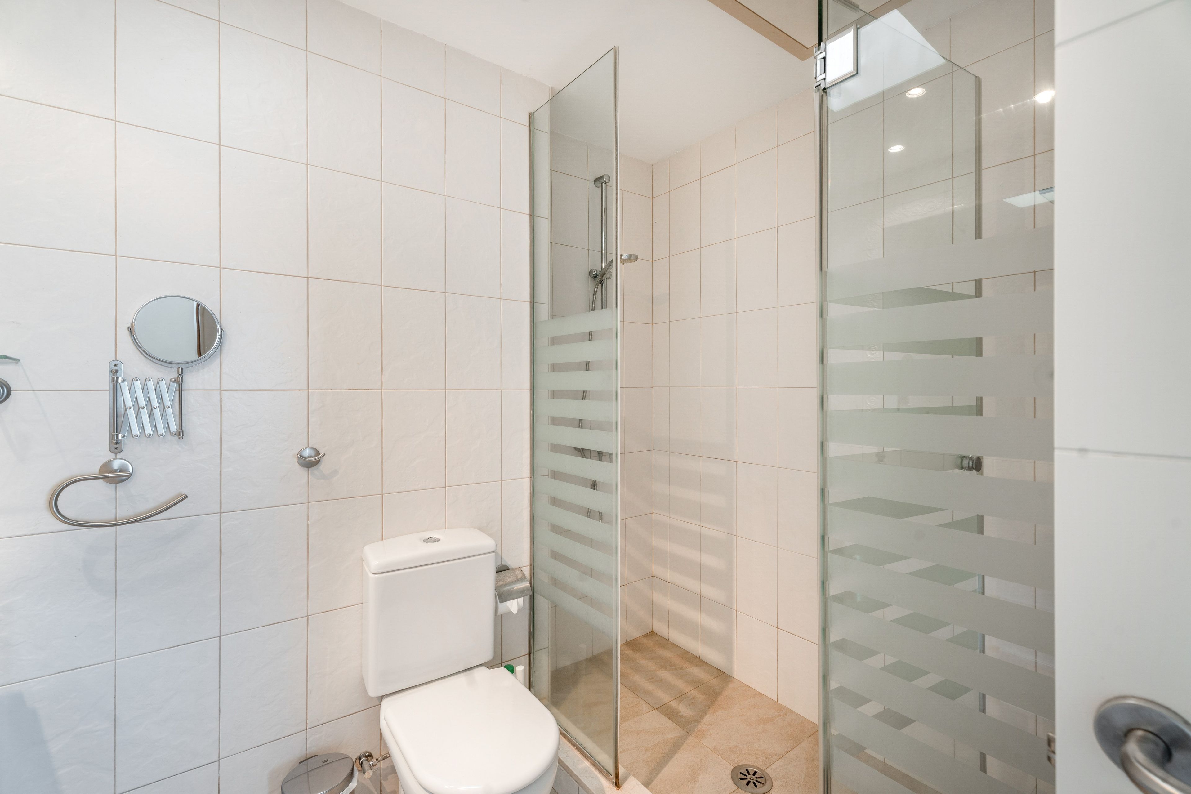Un baño moderno con cabina de ducha de vidrio, un inodoro y un espejo.