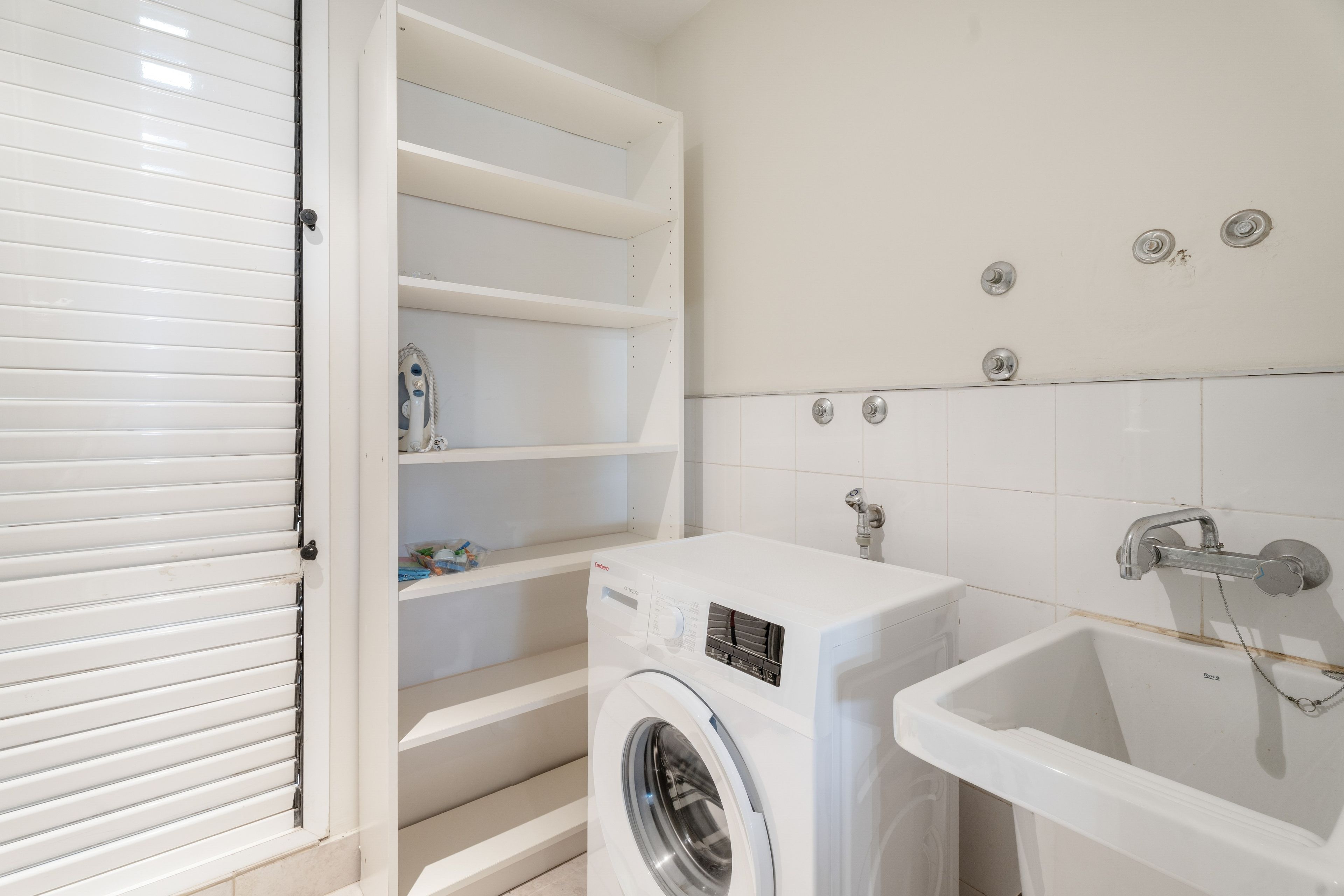 Un cuarto de lavandería con lavadora y lavamanos.