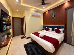 A hotel room with a large bed, a flat-screen TV mounted on the wall, a wooden headboard, and a small potted plant. - BnB By Rama A Luxury Stay (Varanasi)
