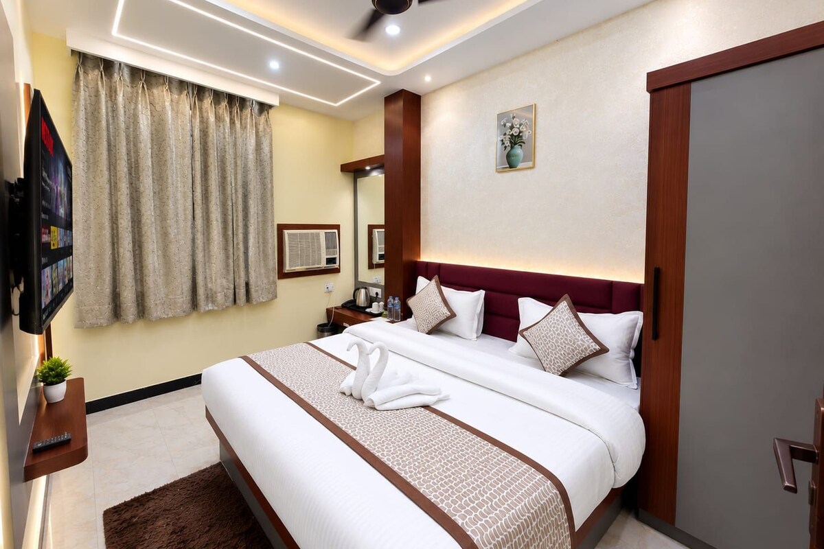 A hotel room with a large bed, a flat-screen TV, a ceiling fan, and a painting on the wall.