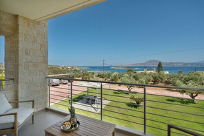 Ein Balkon mit Blick auf das Meer, eine Steinmauer und ein Tisch mit einer Ananas und einem Weinglas.