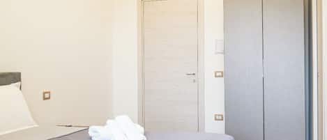 A hotel room with a bed, a wardrobe, and a door.