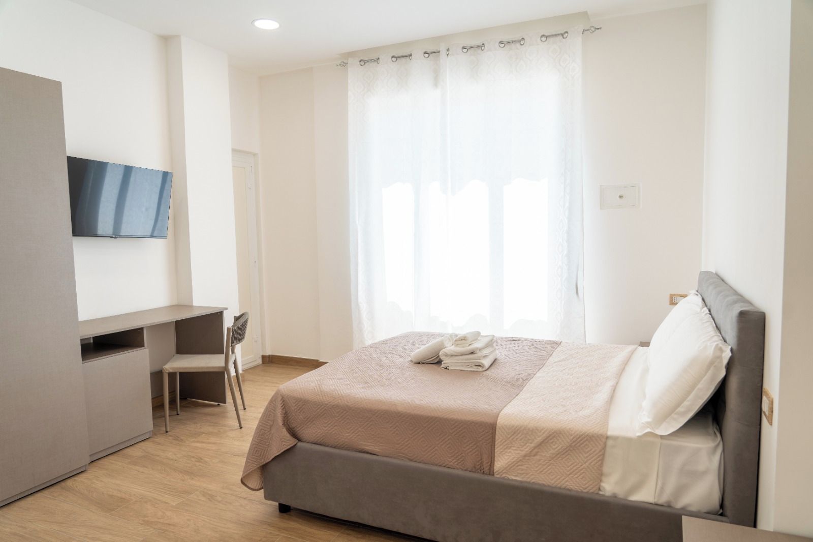 A bedroom with a bed, a desk, and a chair.