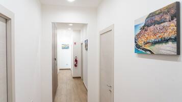 Ein Korridor mit einem an der Wand befestigten Feuerlöscher, einer Tür am Ende und einem Gemälde an der Wand.