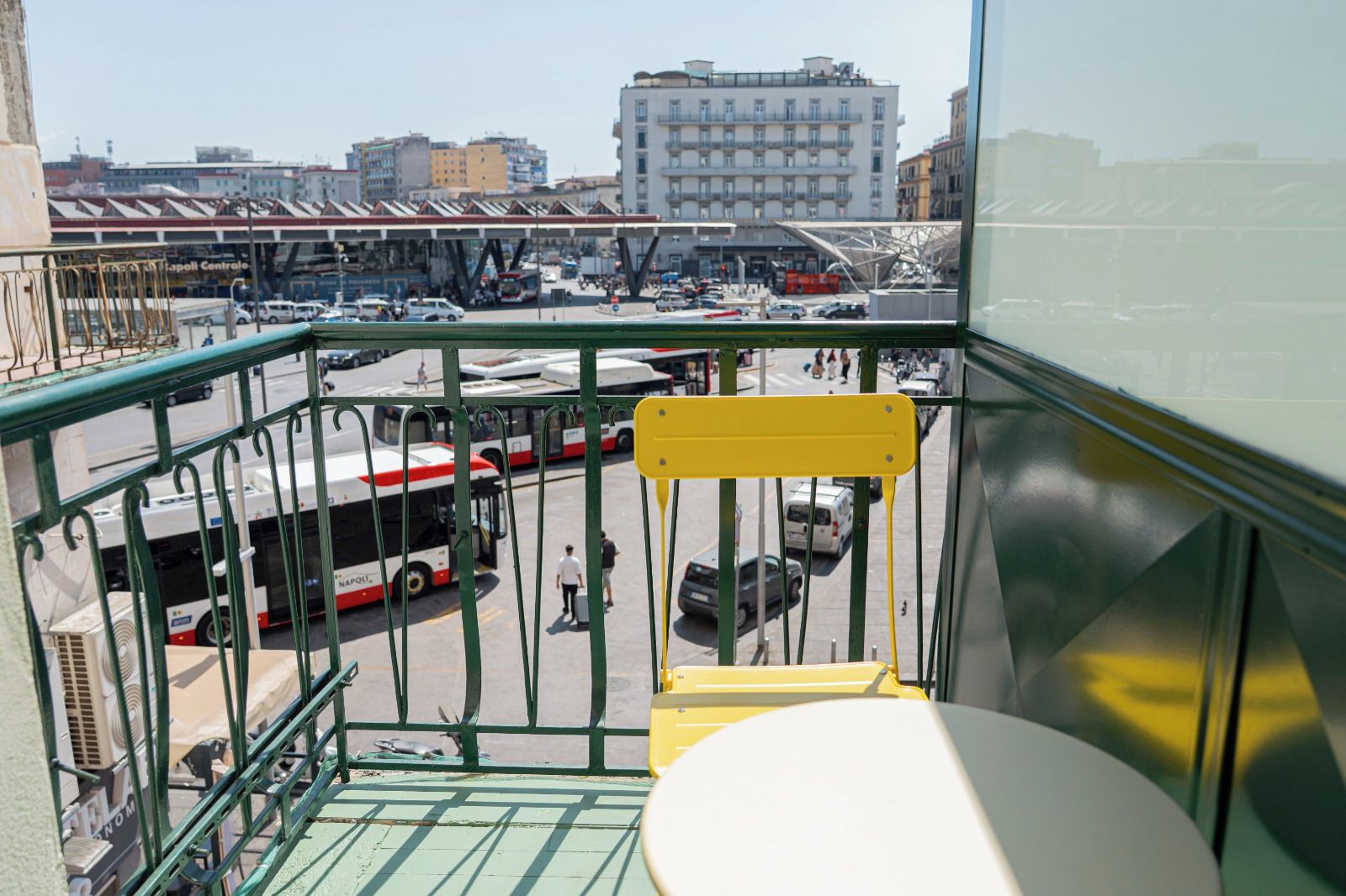 Un balcon donnant sur une gare routière, avec des bâtiments en arrière-plan.
