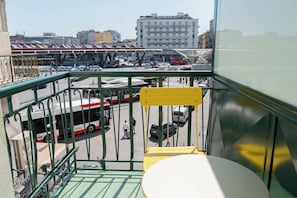 Un balcon donnant sur une gare routière, avec des bâtiments en arrière-plan.