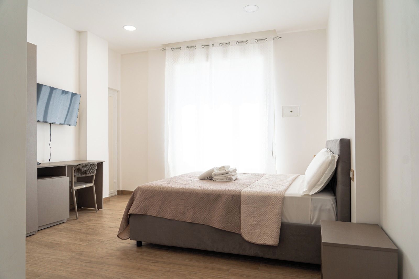 Ein Hotelzimmer mit Bett, Schreibtisch und Fernseher.