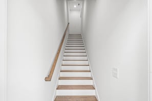 A narrow, white-walled stairway with wooden steps and a wooden handrail. - The Blue Sky 2 blocks to Beach Pets (Myrtle Beach)