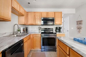 A modern kitchen with wooden cabinets, stainless steel appliances, and a marble countertop. - Rhythm & Tide-Concerts. Coastlines. Charleston. (Charleston)