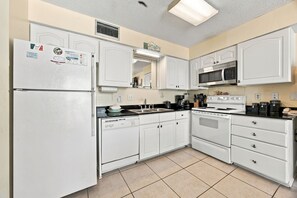 A kitchen with white cabinets, a refrigerator, a microwave, a stove, and a dishwasher. - Beachfront condo w Gulf views, 3 pools, tennis & fitness room ~ Sleep 6 (Orange Beach)