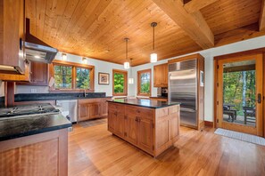A modern kitchen with wooden cabinets, a stainless steel refrigerator, and a large island. - 4 Bedroom Stowe Apres Retreat (Stowe)