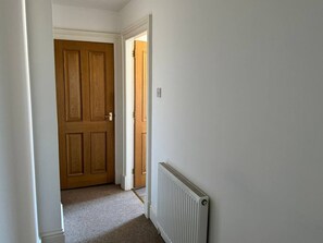 A hallway with a wooden door and a radiator on the wall. - Town Centre Flat For Two Adults (Perth and Kinross)