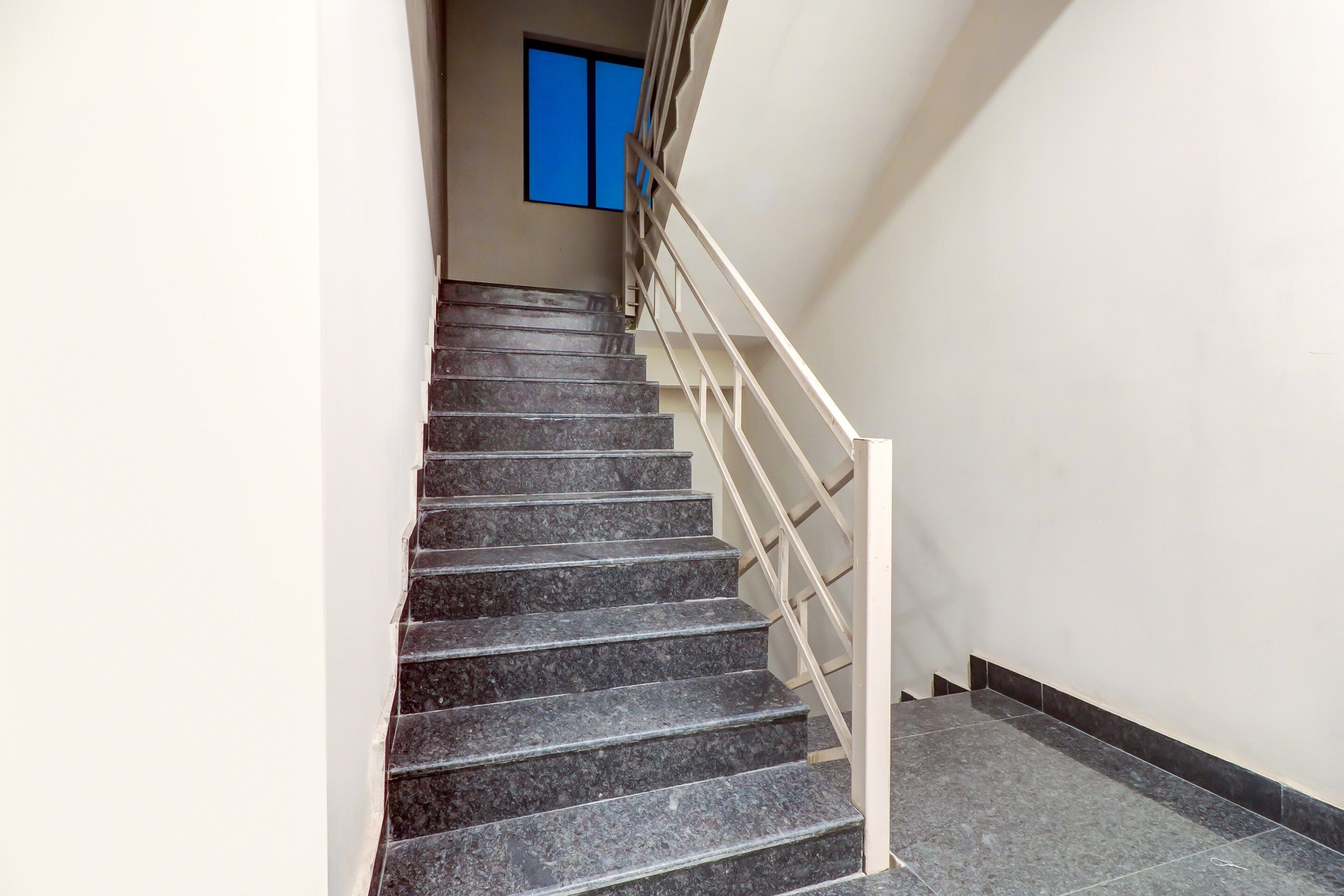 A staircase with a handrail and a window with blue framing.